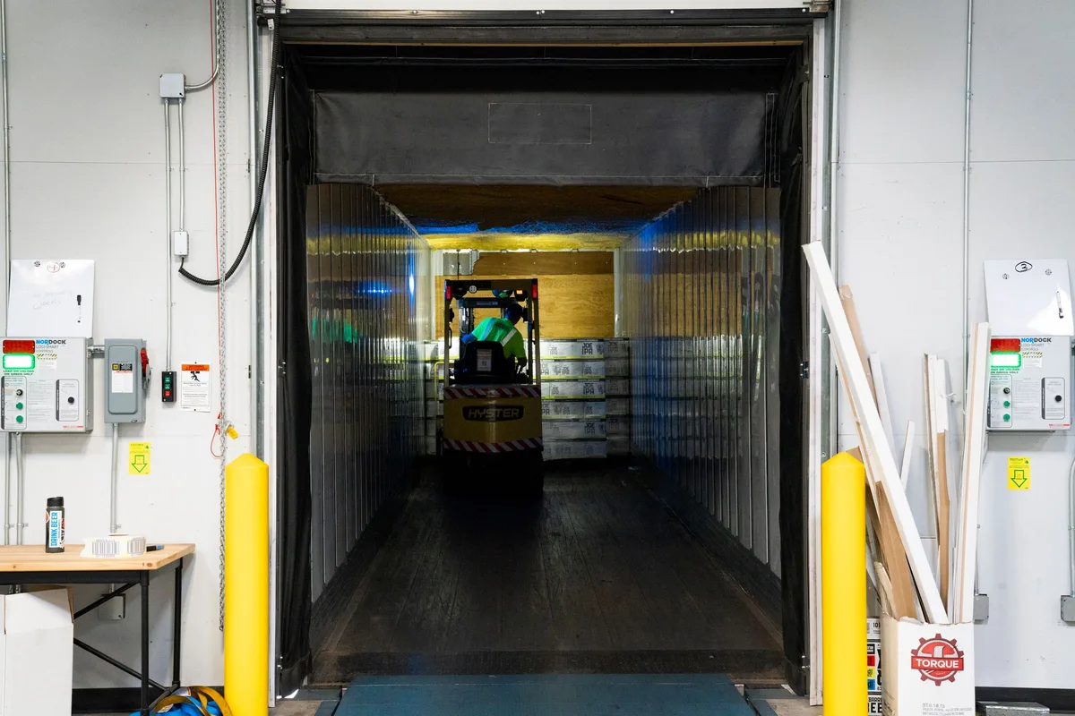 Forklift with a worker passing through strip curtains into a cold-storage room