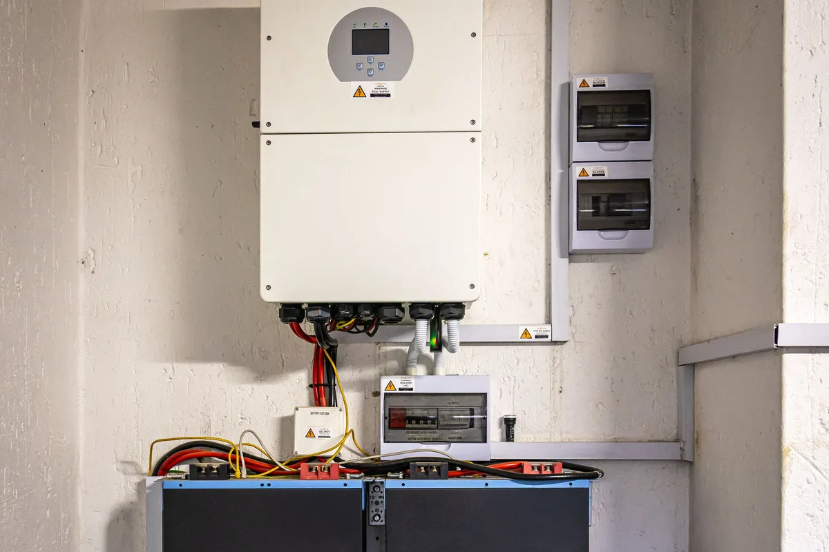 Four 51.2 V rack-mounted home ESS batteries beneath a wall inverter for time-of-use load shifting