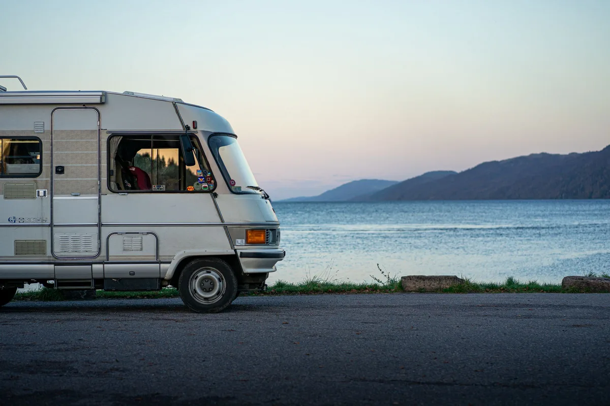Motorhome parked by a lakeshore at dusk, illustrating an RV house battery upgrade
