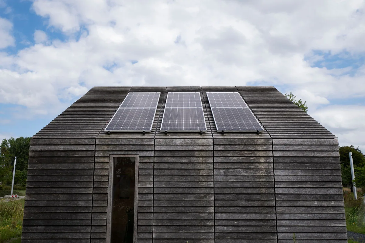Timber off-grid cabin with three solar panels mounted on its roof