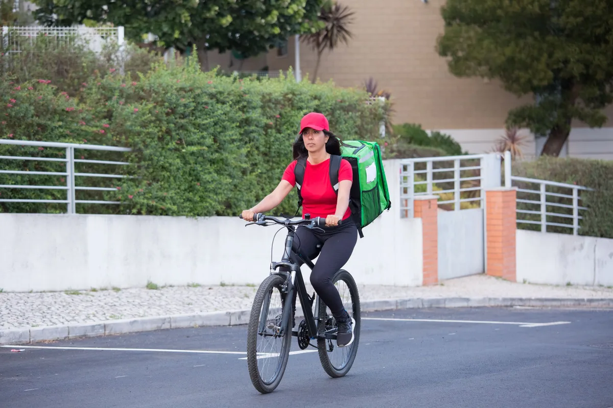Courier on an e-bike carrying an insulated delivery bag through the city